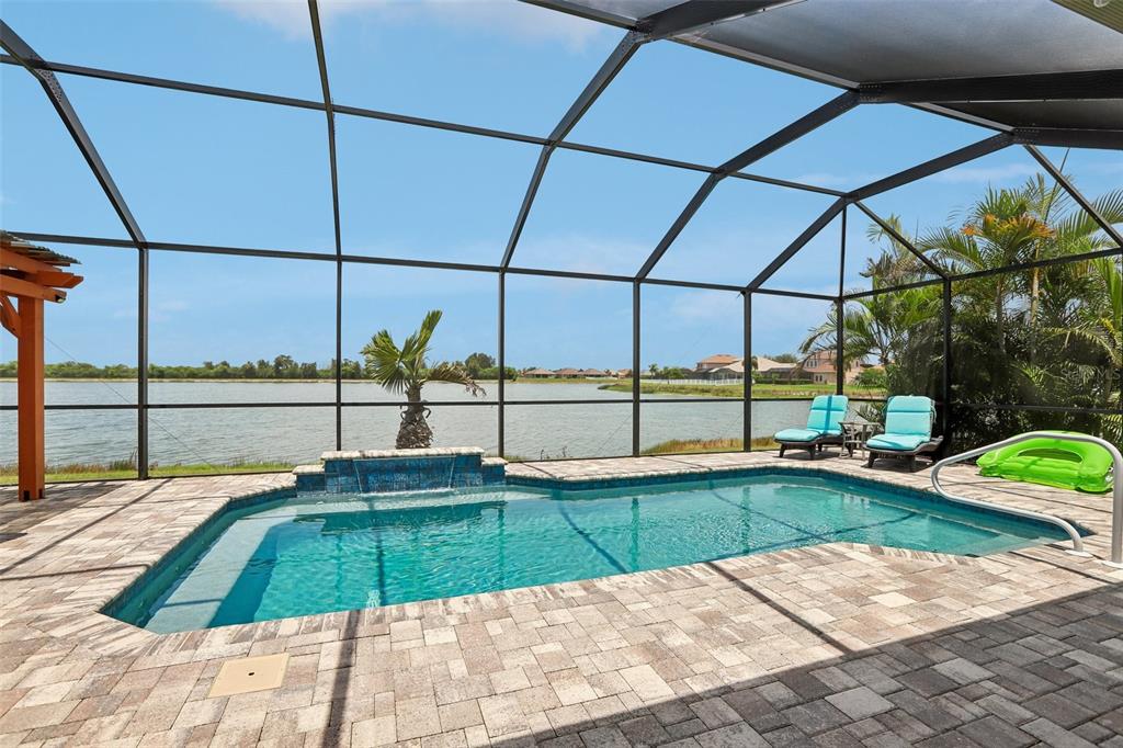 A screened-in pool patio features a paved deck, a water feature, and a lake view — 809 SEMINOLE SKY DRIVE, RUSKIN, FL