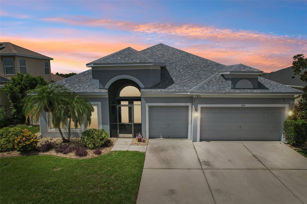 A single-story house with a gray exterior, a two-car garage, and a covered entryway — 809 SEMINOLE SKY DRIVE, RUSKIN, FL