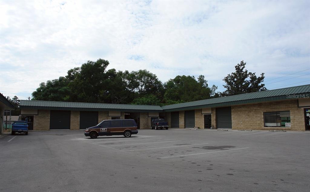 An exterior view of a single-story commercial building with multiple garage doors and parking spaces — 1706 N MAGNOLIA AVENUE, OCALA, FL