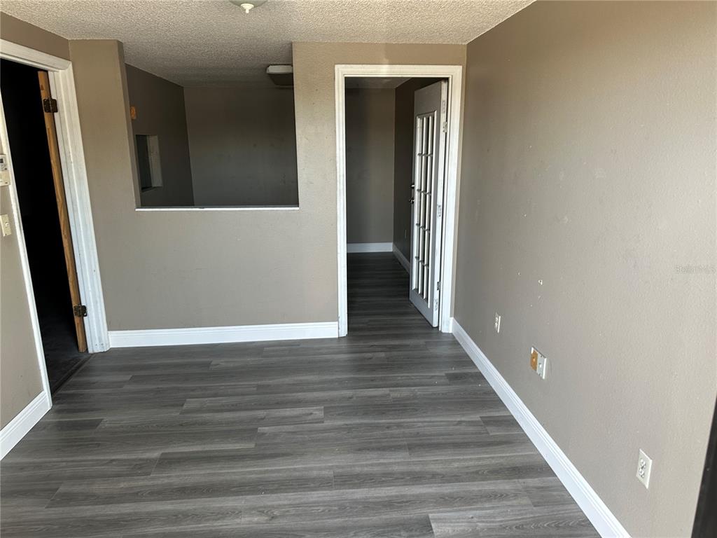 An interior room features gray wood-look flooring, beige walls, and two doorways — 1706 N MAGNOLIA AVENUE, OCALA, FL