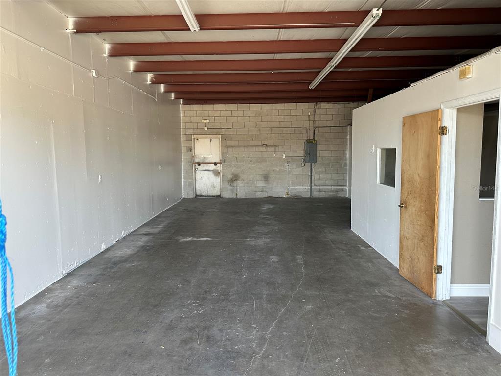 An interior view of a warehouse space with concrete floors, block walls, and exposed beams — 1706 N MAGNOLIA AVENUE, OCALA, FL