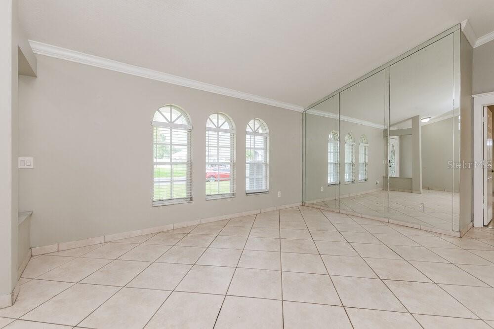 A room with light-colored tile floors, three arched windows, and a large mirrored wall — 2708 ASHLEY COURT, KISSIMMEE, FL