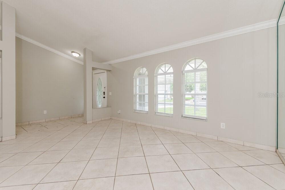 An empty room features light-colored tile flooring, neutral walls, and three arched windows — 2708 ASHLEY COURT, KISSIMMEE, FL