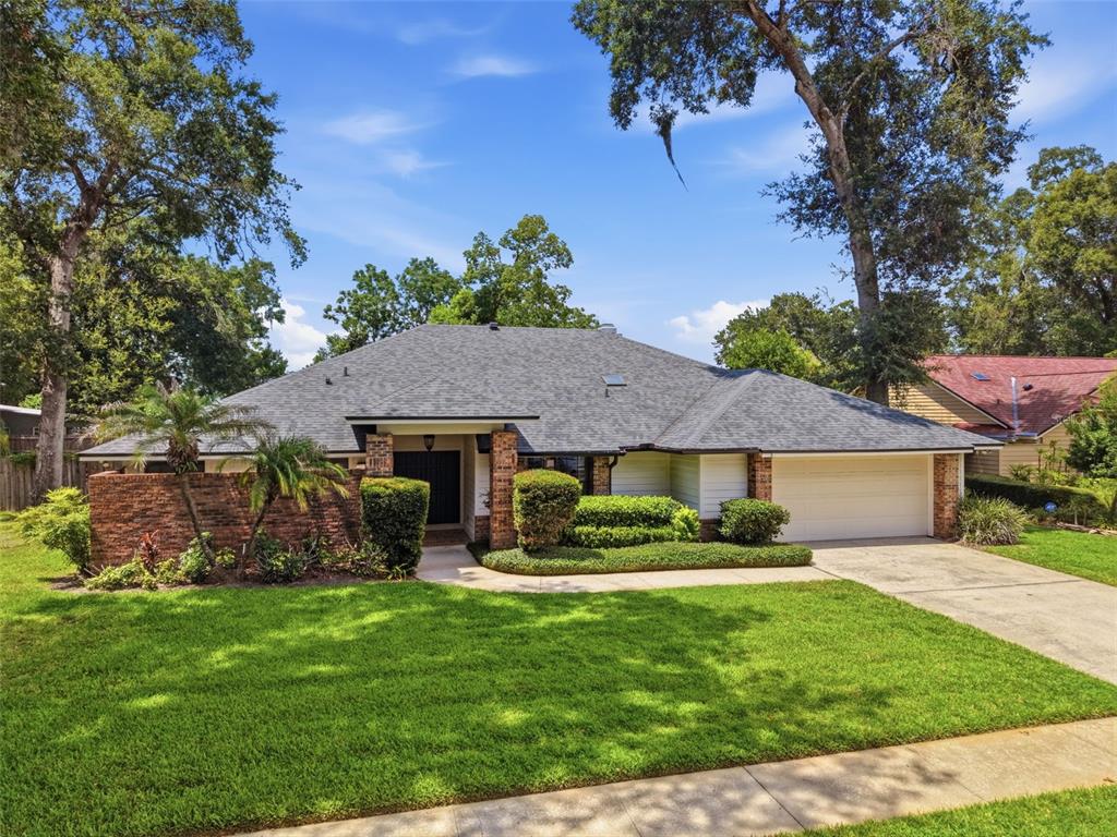 A single-story brick and siding house with a gray shingled roof and a two-car garage — 2309 SWEETWATER COUNTRY CLUB PLACE DRIVE, APOPKA, FL