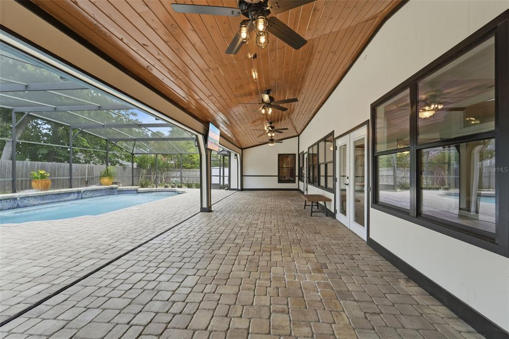 A covered patio with a wood-paneled ceiling, ceiling fans, and a view of a pool — 2309 SWEETWATER COUNTRY CLUB PLACE DRIVE, APOPKA, FL