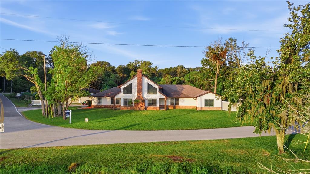 A single-story house with a brick chimney and two triangular gables sits on a lawn — 212 PLEASANT STREET, LAKE HELEN, FL