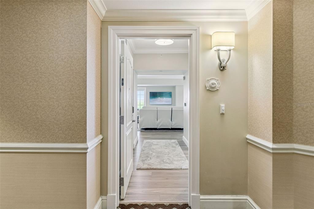 A view through an open doorway into a room with light wood flooring and furniture — 7593 GATHERING DRIVE UNIT 503, REUNION, FL