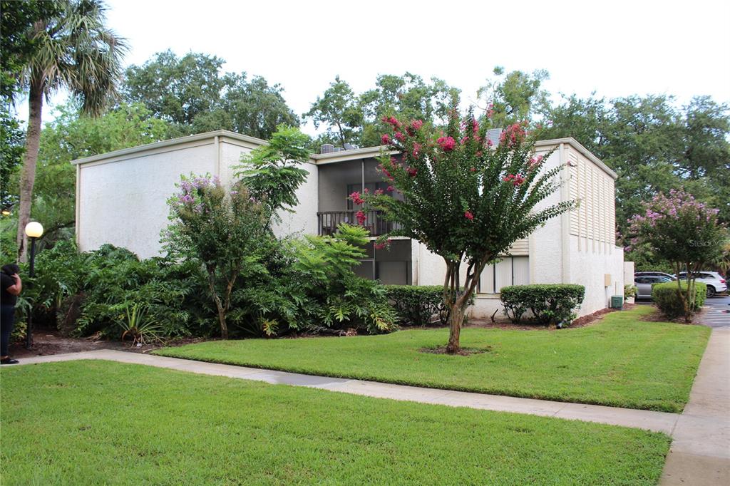A two-story apartment building with a screened balcony, surrounded by green lawns and trees — 3294 S SEMORAN BOULEVARD UNIT 15, ORLANDO, FL