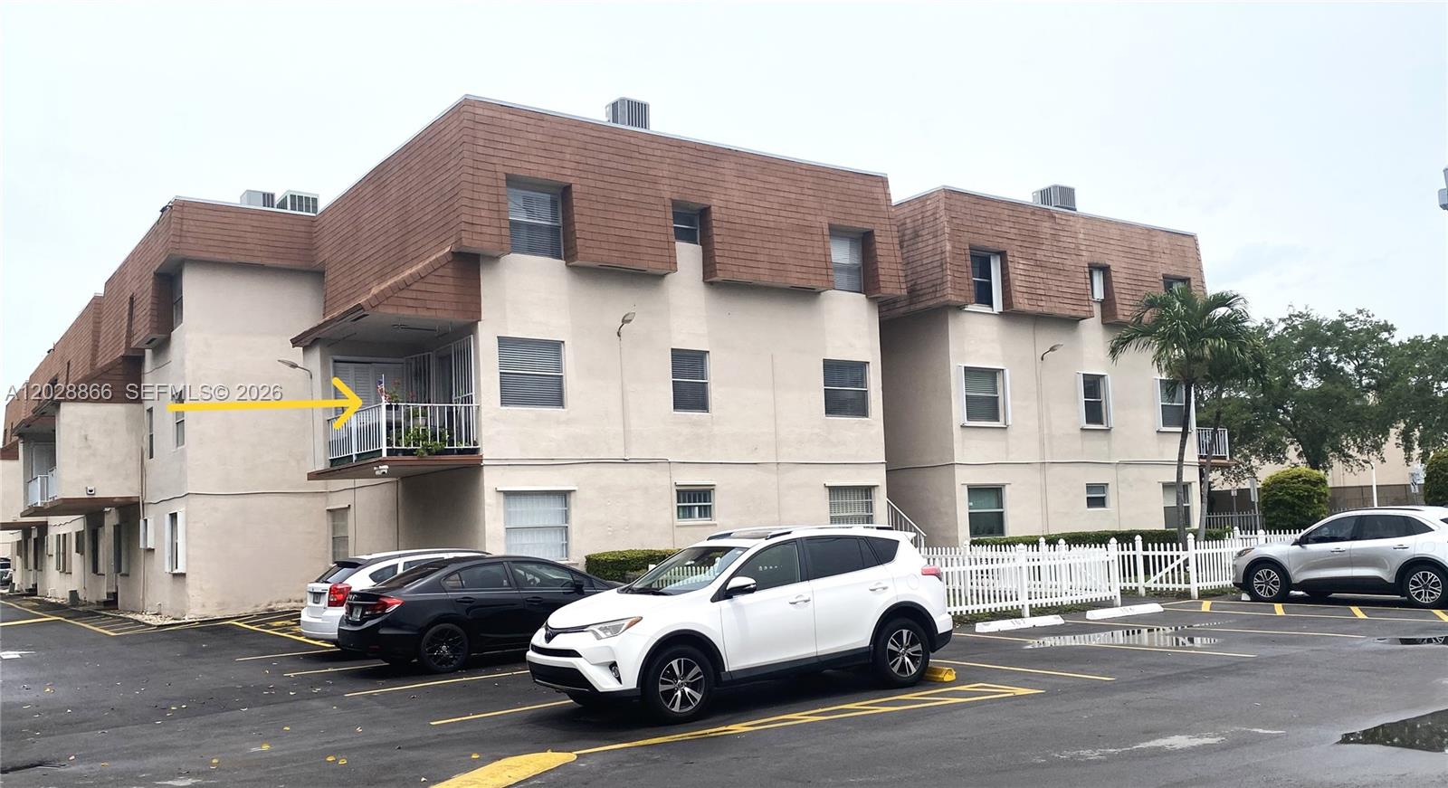 An exterior view of a multi-story apartment building with a parking lot in front — 1570 W 46th St # 214, Hialeah FL 33012, HIALEAH, FL