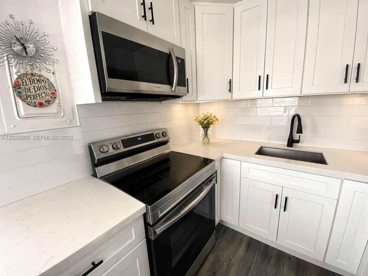 A kitchen features white cabinets, stainless steel appliances, a subway tile backsplash, and quartz countertops — 1570 W 46th St # 214, Hialeah FL 33012, HIALEAH, FL