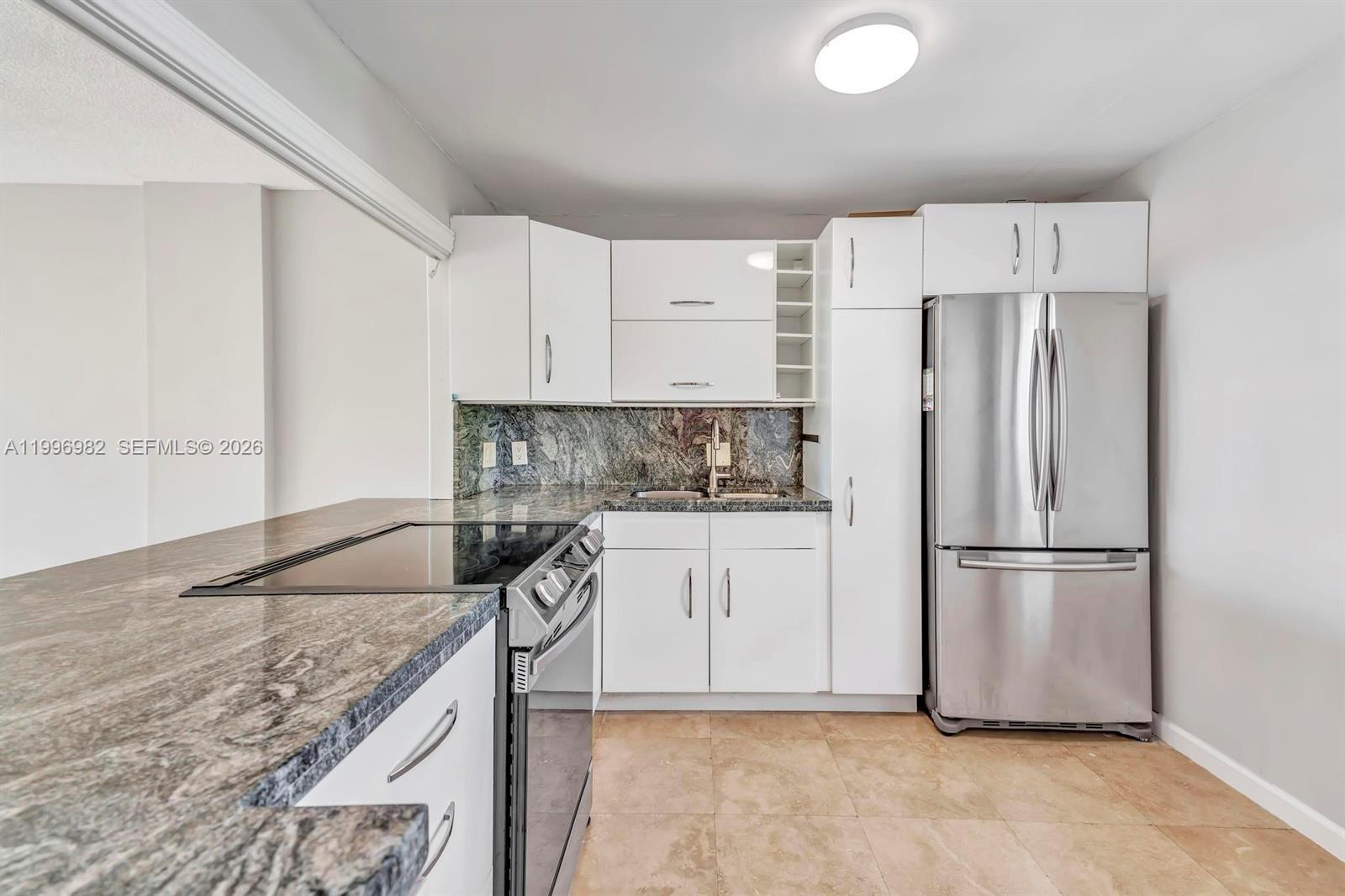 A kitchen features white cabinets, stainless steel appliances, and dark granite countertops — 3199 S Ocean Dr # 406, Hallandale Beach FL 33009, HALLANDALE BEACH, FL