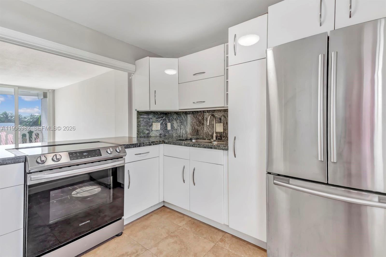 A kitchen features white cabinets, stainless steel appliances, and dark granite countertops — 3199 S Ocean Dr # 406, Hallandale Beach FL 33009, HALLANDALE BEACH, FL