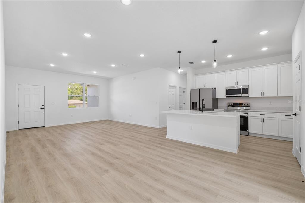 An open-concept kitchen and living area features white cabinets, stainless steel appliances, and light flooring — 254 W BRIMSON PLACE, CITRUS SPRINGS, FL