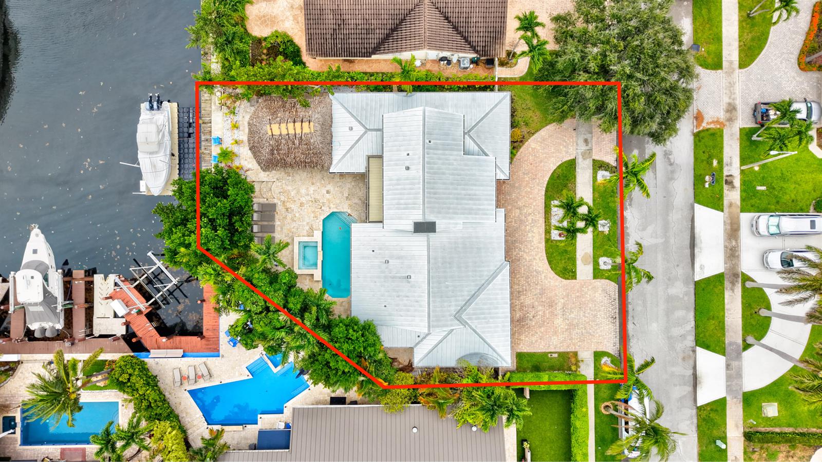 An aerial view shows a waterfront house with a pool, tiki hut, and paved driveway — 1511 SE 12th Court, Deerfield Beach FL 33441, DEERFIELD BEACH, FL