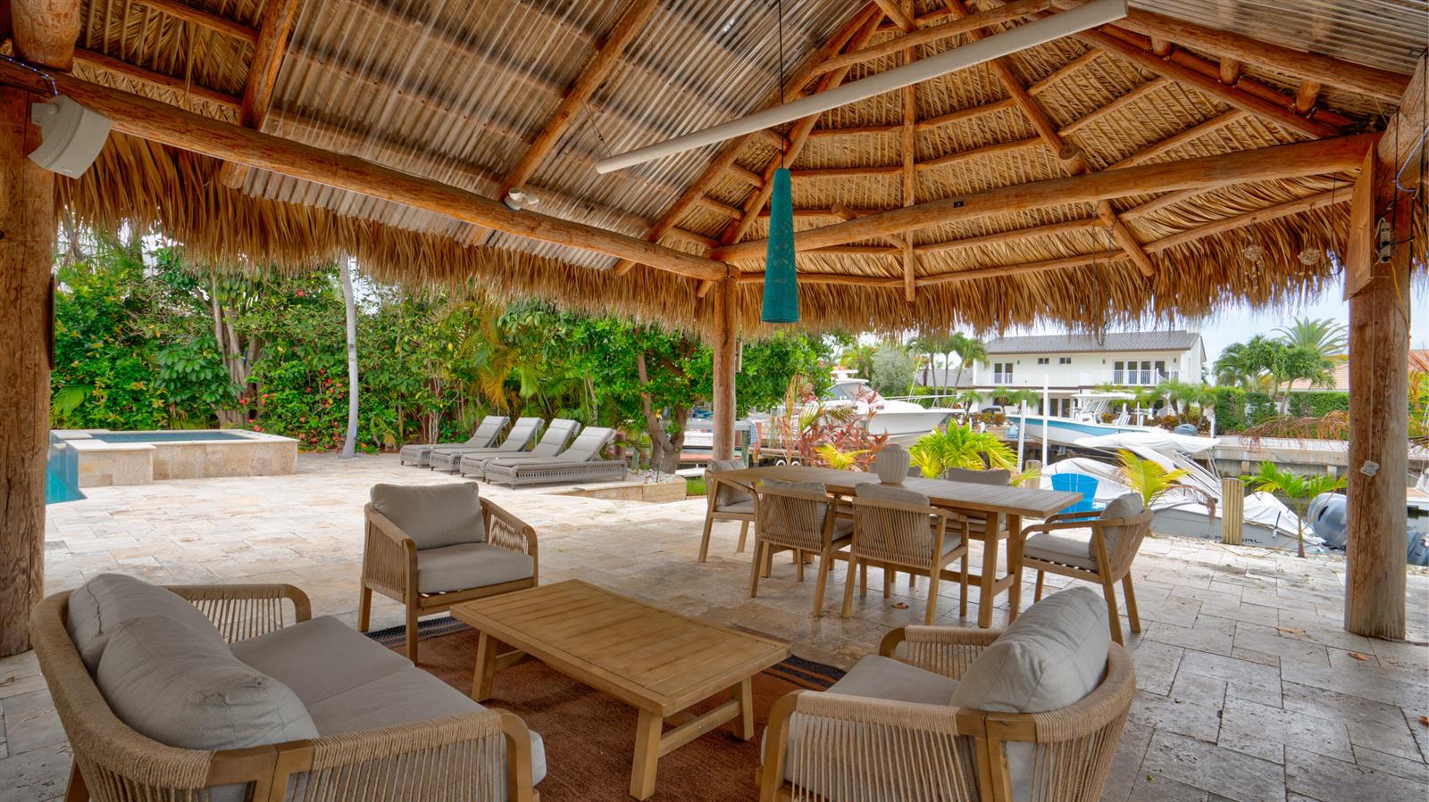 A covered outdoor patio with a thatched roof, dining area, lounge seating, and boat dock — 1511 SE 12th Court, Deerfield Beach FL 33441, DEERFIELD BEACH, FL