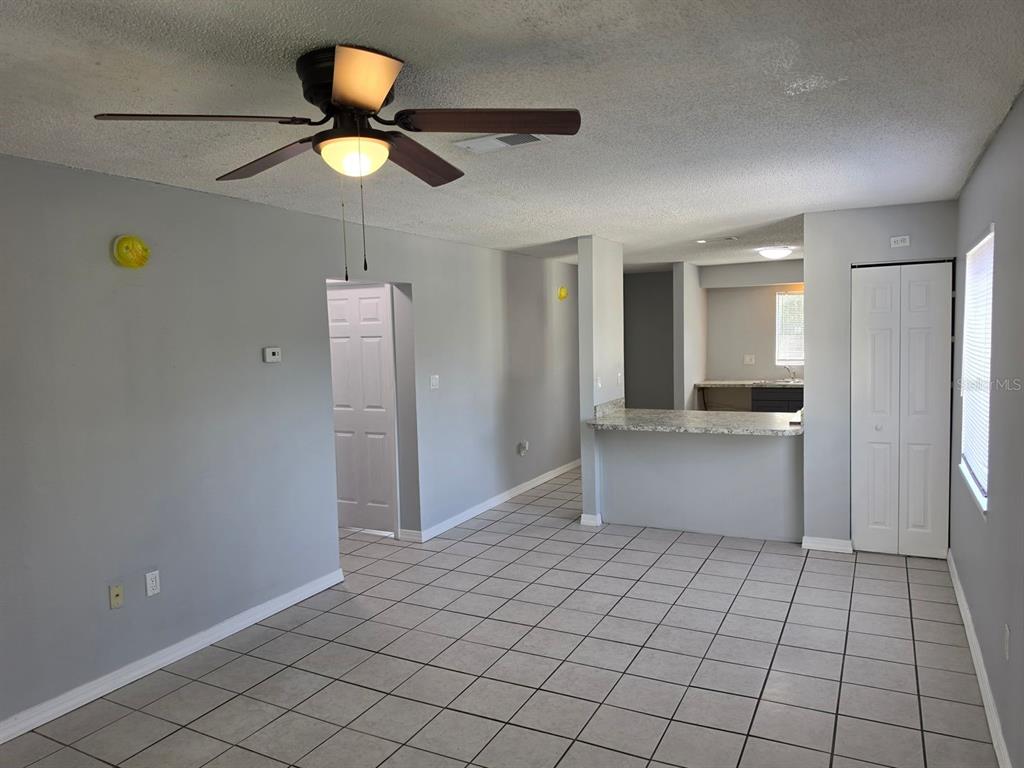 A living area with tile flooring, a ceiling fan, and a pass-through kitchen counter — 2526 S OAK AVENUE UNIT A, SANFORD, FL