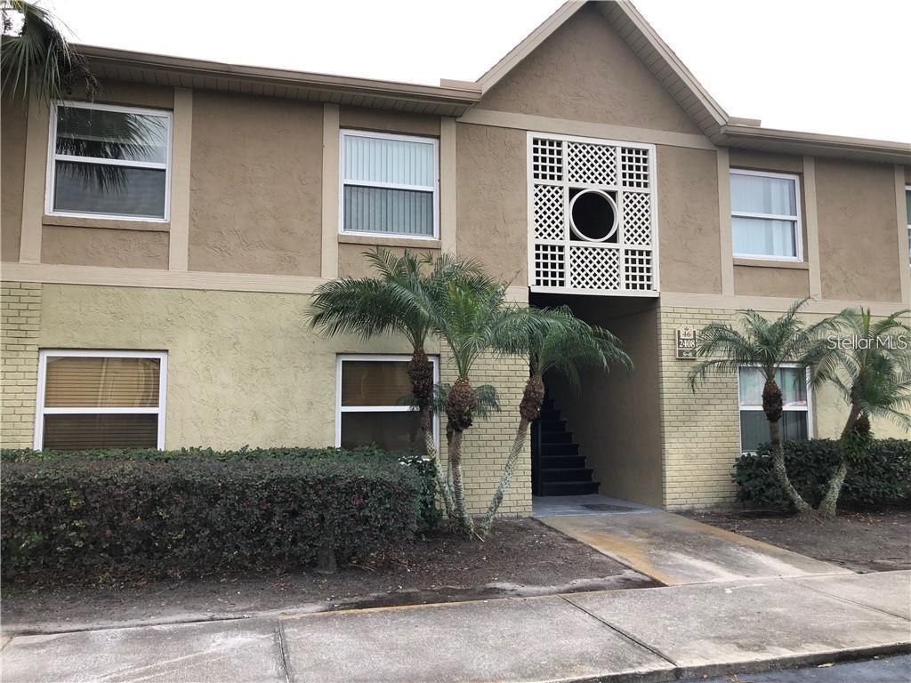 A two-story apartment building exterior features tan stucco, brick accents, and palm trees — 2408 SWAILES DRIVE UNIT 7, ORLANDO, FL