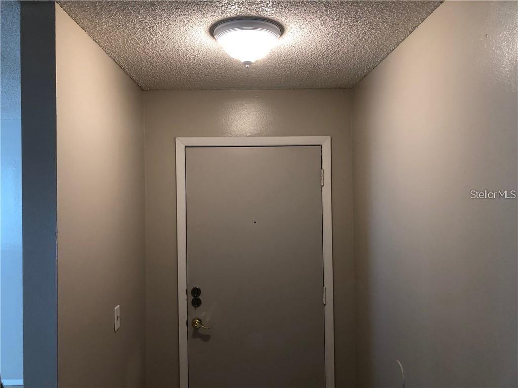 An entryway features a gray door, a textured ceiling, and a flush-mount light fixture — 2408 SWAILES DRIVE UNIT 7, ORLANDO, FL