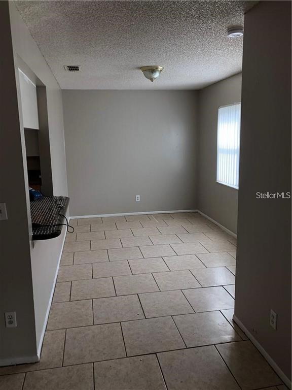 An empty dining area features beige tile flooring, light gray walls, and a window with blinds — 2408 SWAILES DRIVE UNIT 7, ORLANDO, FL