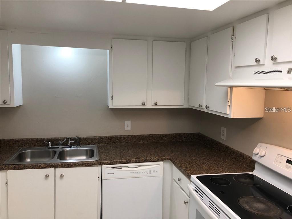 A kitchen features white cabinets, a double-basin sink, a dishwasher, and a dark laminate countertop — 2408 SWAILES DRIVE UNIT 7, ORLANDO, FL