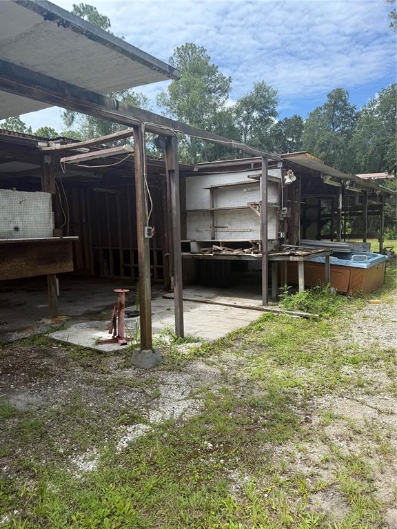 An open-air, unfinished wooden structure with a hot tub and workbenches on a gravel lot — 2857 W NEW YORK AVENUE, DELAND, FL