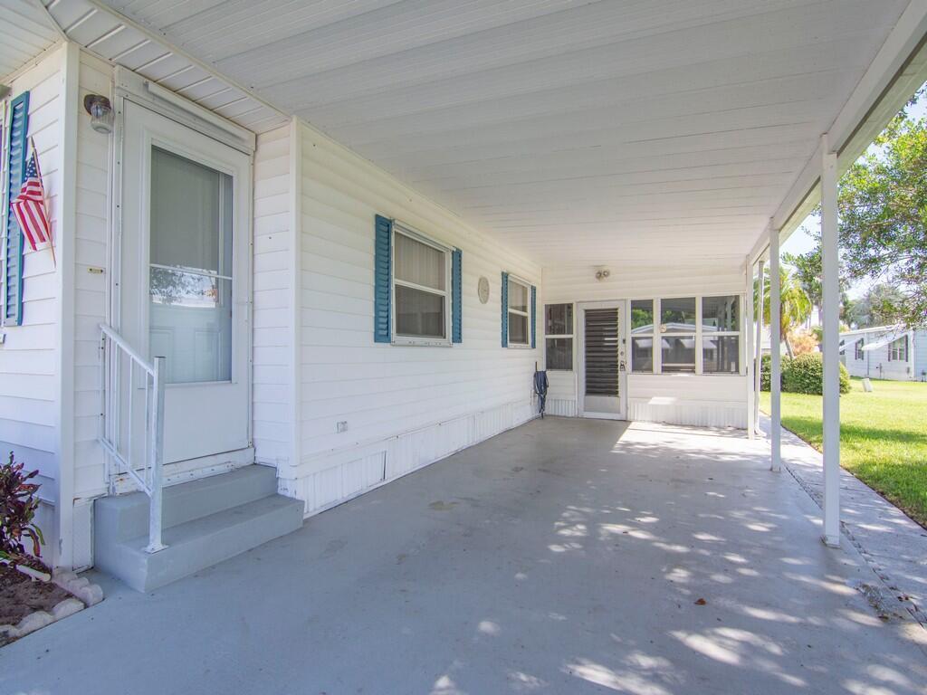 A white mobile home exterior features a covered carport, concrete driveway, and a small staircase — 264 NE Cameo Way, Jensen Beach FL 34957, JENSEN BEACH, FL