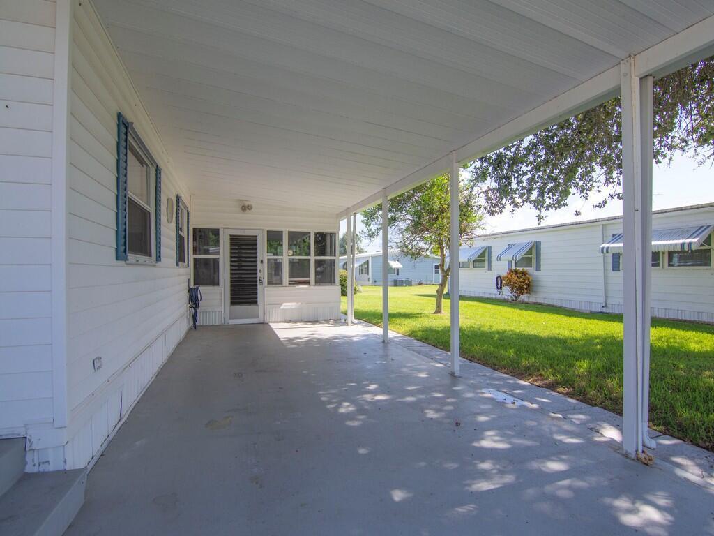 A covered concrete carport extends along the side of a white mobile home — 264 NE Cameo Way, Jensen Beach FL 34957, JENSEN BEACH, FL