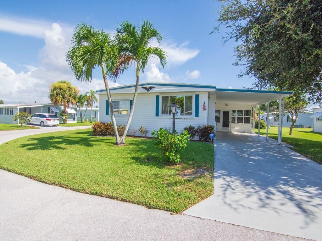A single-story mobile home with a carport, palm trees, and a green lawn — 264 NE Cameo Way, Jensen Beach FL 34957, JENSEN BEACH, FL