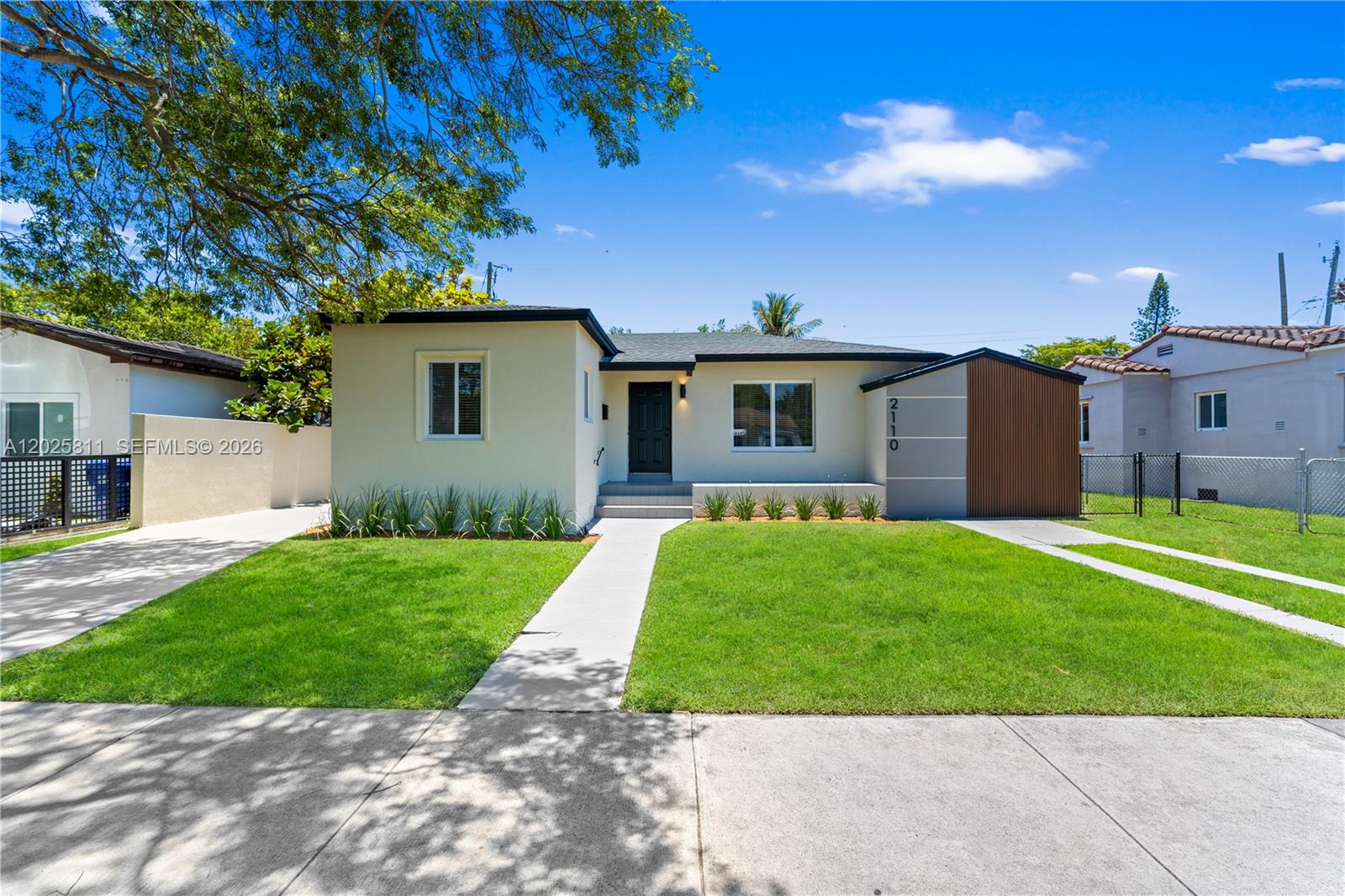 A single-story house with a light-colored exterior, a dark front door, and a wooden accent wall — 2110 SW 15th St, Miami FL 33145, MIAMI, FL