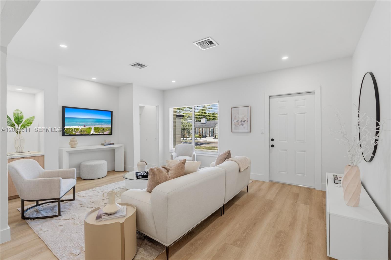 A bright living room features light wood floors, white walls, a sofa, and a television — 2110 SW 15th St, Miami FL 33145, MIAMI, FL