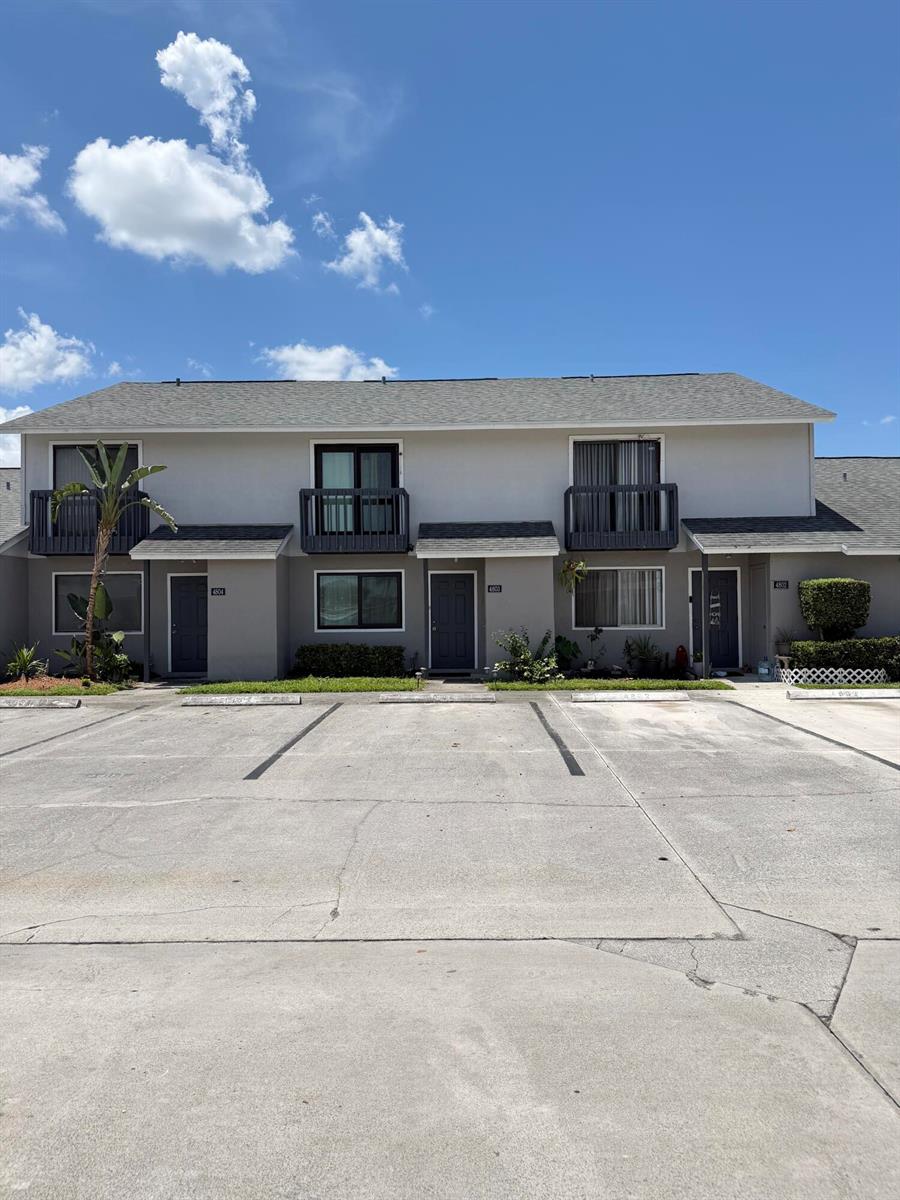 A two-story apartment building with gray siding, dark doors, and balconies under a blue sky — 4803 Pier Drive, FL 33463, FL