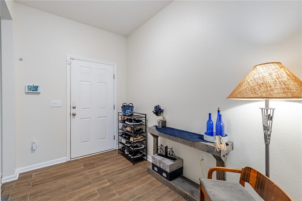 An entryway features wood-look tile flooring, a white door, a shoe rack, and a console table — 346 EAGLECREST DRIVE, HAINES CITY, FL