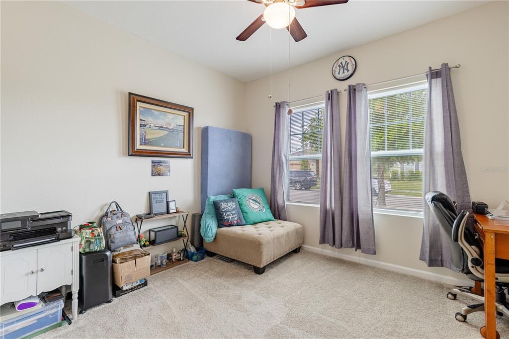 A bedroom features a beige tufted ottoman, a desk, and two windows with gray curtains — 346 EAGLECREST DRIVE, HAINES CITY, FL