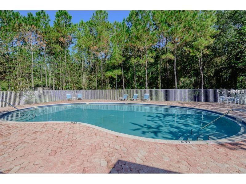 An outdoor swimming pool with a brick paver deck surrounded by a fence and trees — 8563 HUNTERS KEY CIRCLE, TAMPA, FL
