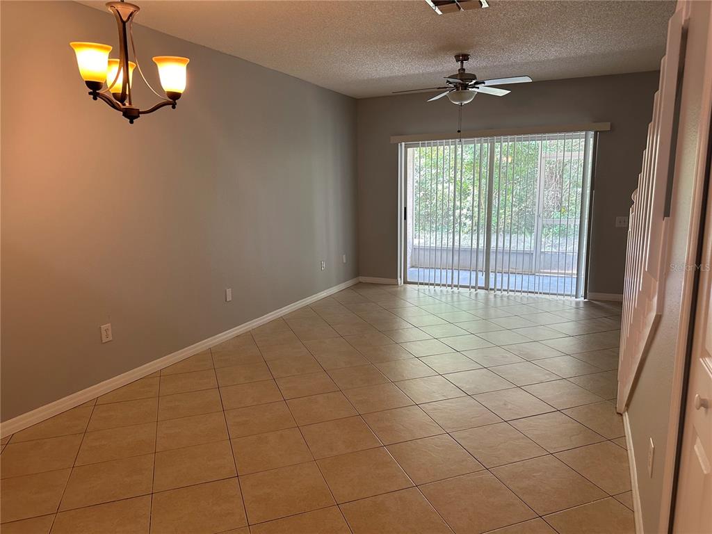 A dining area with tile flooring, a chandelier, a ceiling fan, and sliding glass doors — 8563 HUNTERS KEY CIRCLE, TAMPA, FL