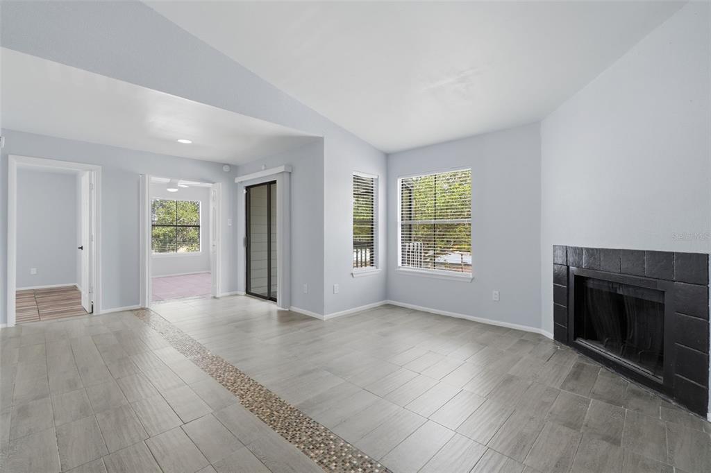A living room features gray tile flooring, a black tiled fireplace, and a sliding glass door — 3716 IDLEBROOK CIRCLE UNIT 212, CASSELBERRY, FL