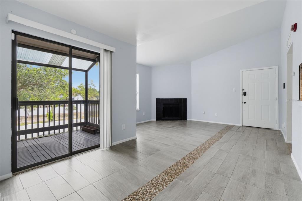 A living room with light gray tile flooring, a black fireplace, and a screened-in balcony — 3716 IDLEBROOK CIRCLE UNIT 212, CASSELBERRY, FL