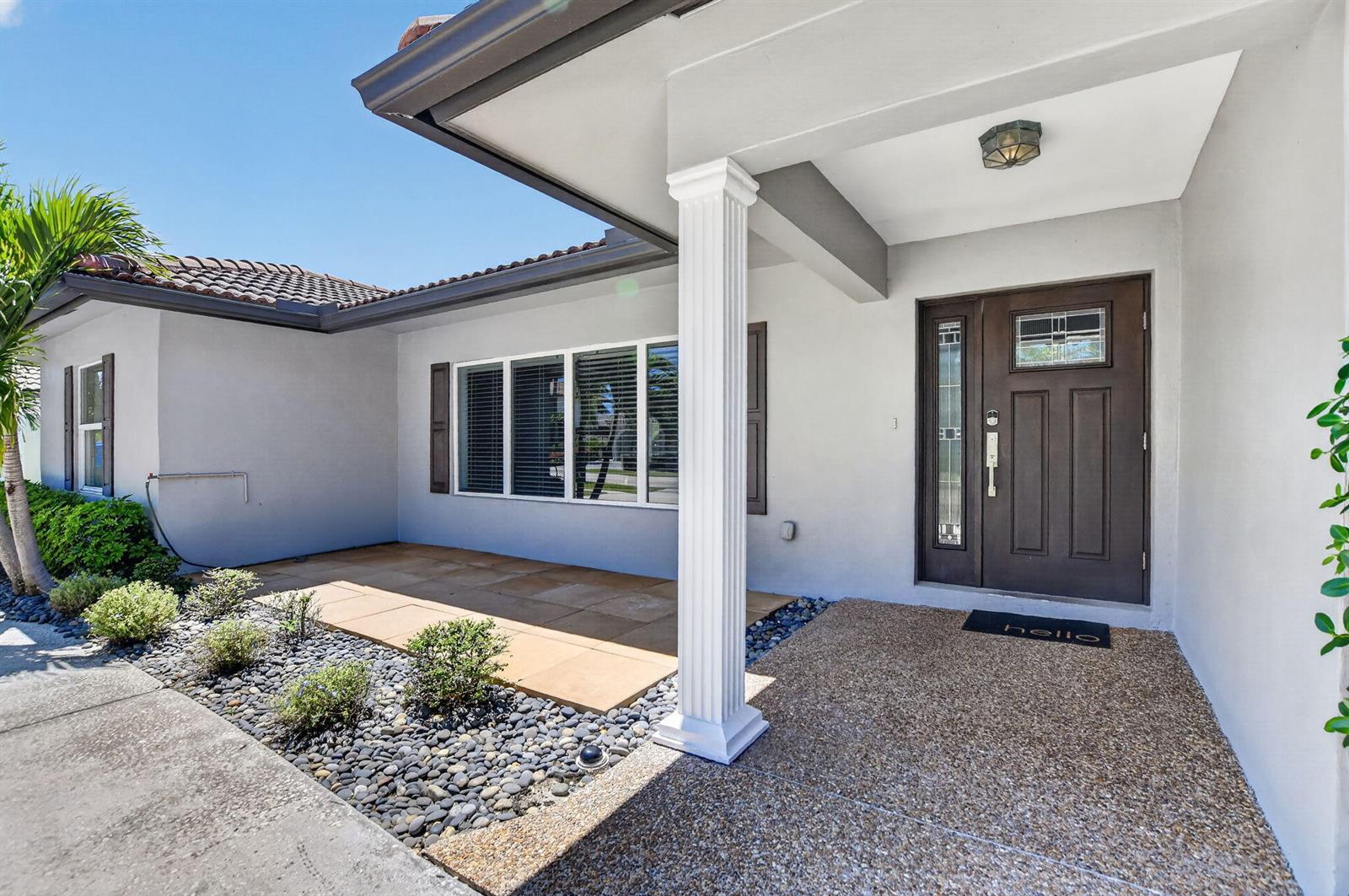 The exterior of a house features a covered entryway with a column and a front door — 650 SW 16th Street, Boca Raton FL 33486, BOCA RATON, FL