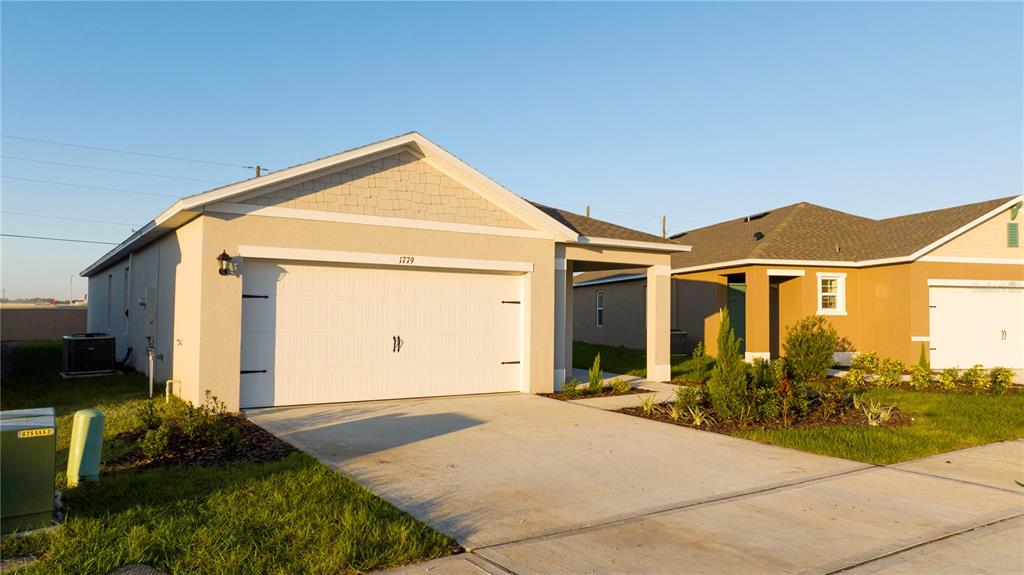 A beige single-story house with a two-car garage and a concrete driveway — 1779 POST OAK DRIVE, DAVENPORT, FL