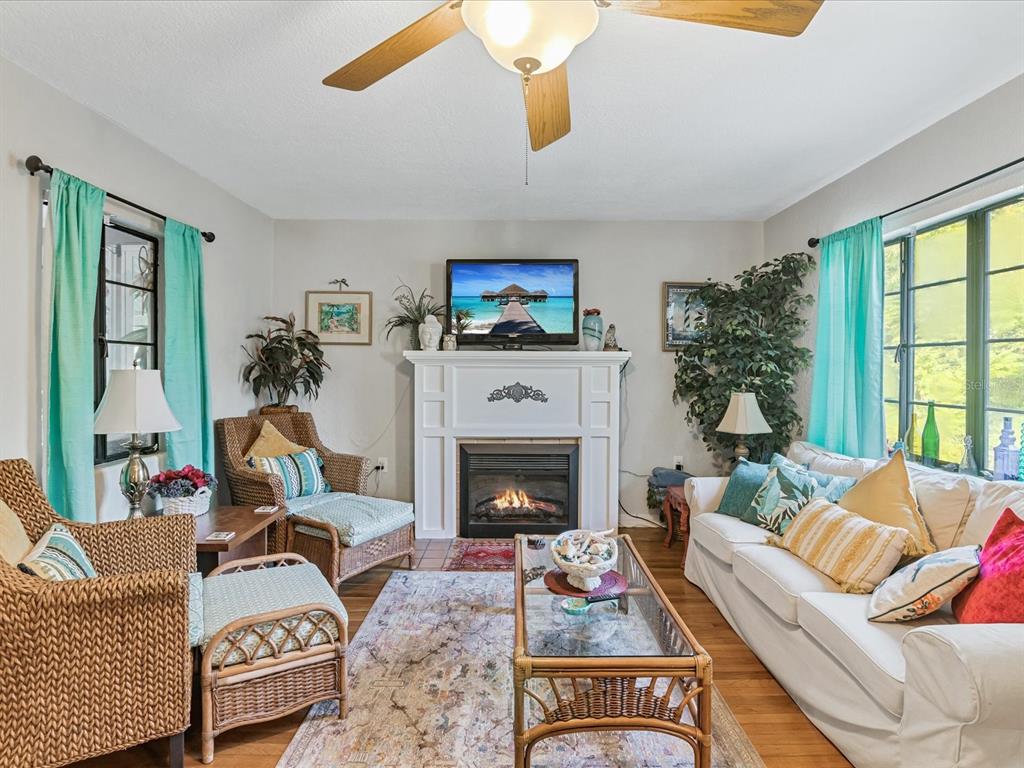 A living room features a fireplace, a television, wicker furniture, and light-colored walls — 5638 VIRGINIA AVENUE, NEW PORT RICHEY, FL