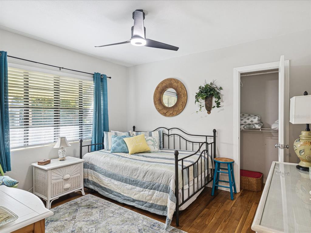 A bedroom features a daybed, a white nightstand, a ceiling fan, and a walk-in closet — 5638 VIRGINIA AVENUE, NEW PORT RICHEY, FL