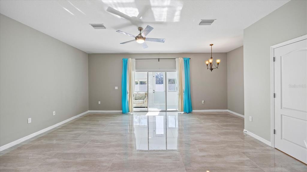 A spacious room with light gray walls, large tile flooring, and a ceiling fan — 12843 BUFFALO RUN DRIVE, GIBSONTON, FL