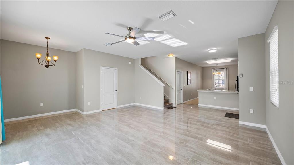 An open-concept living and dining area features light gray tile flooring and a ceiling fan — 12843 BUFFALO RUN DRIVE, GIBSONTON, FL