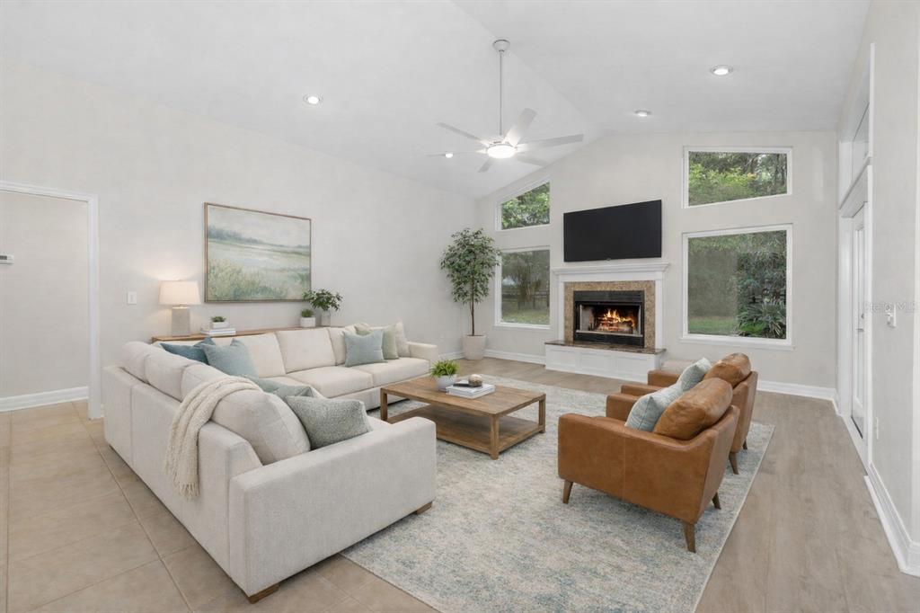A bright living room features a vaulted ceiling, fireplace, sectional sofa, and two leather chairs — 8600 SW 103RD AVENUE, GAINESVILLE, FL