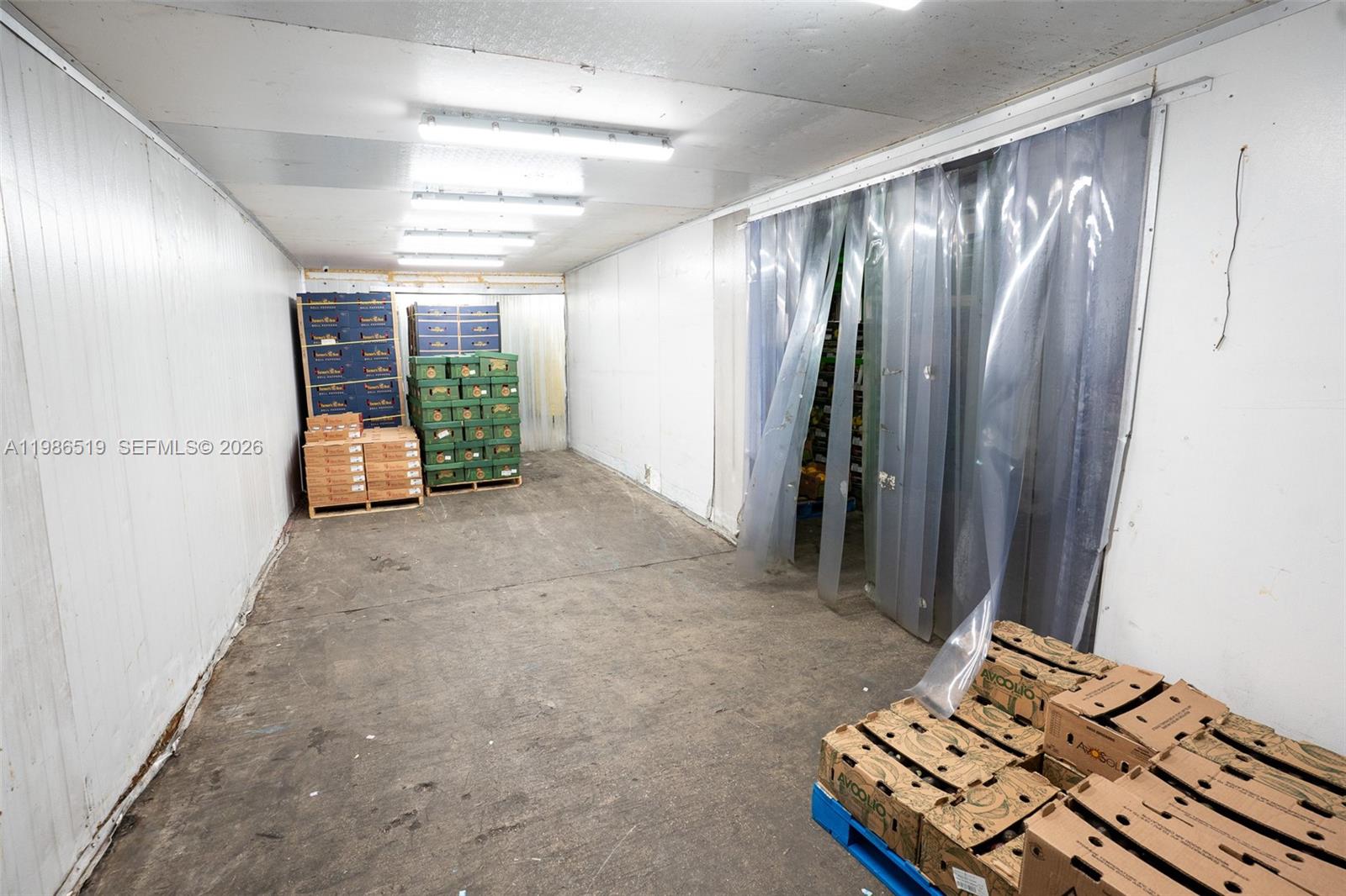 A commercial walk-in cooler features white walls, concrete flooring, and stacked produce crates — 1227 NW 21st Street, FL 33142, FL