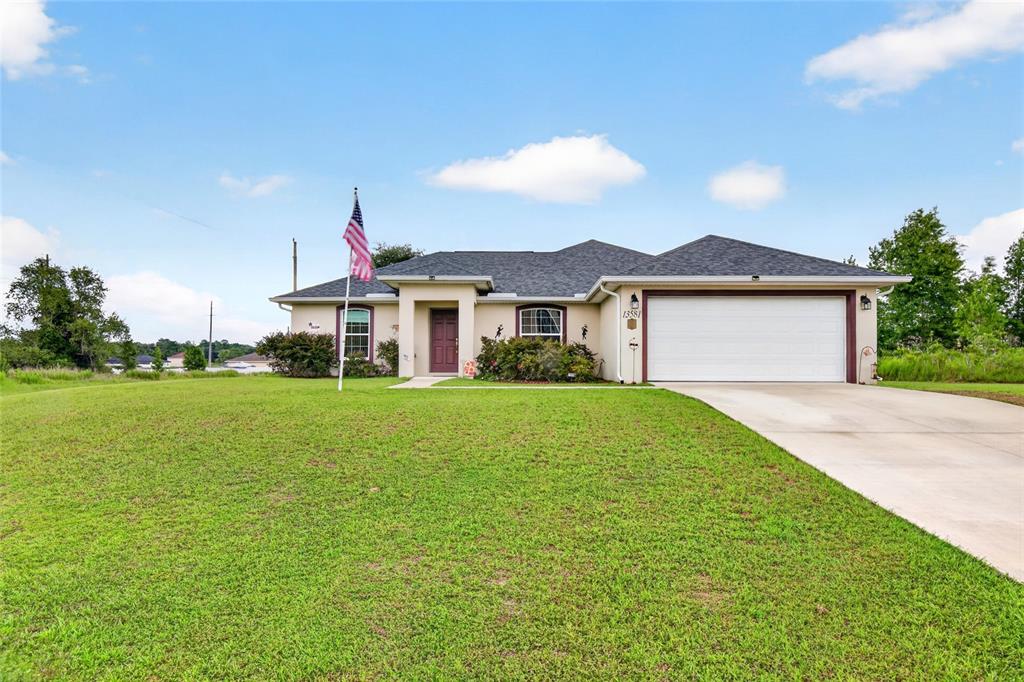 A single-story house with a white garage, a brown front door, and an American flag — 13581 SW 48TH COURT, OCALA, FL