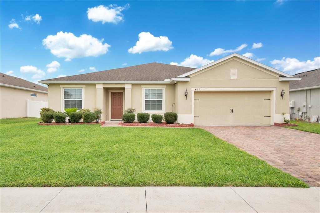 A single-story house with a tan stucco exterior, a two-car garage, and a paved driveway — 4313 TIGRIS DRIVE, APOPKA, FL