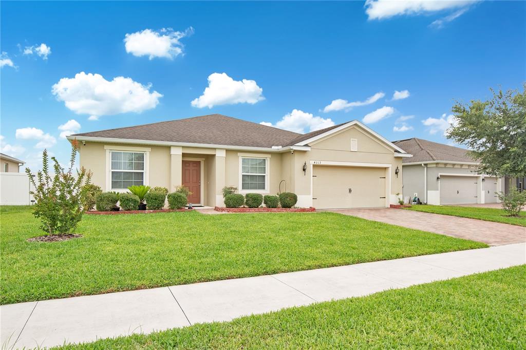 A single-story suburban house with a tan stucco exterior, a two-car garage, and green lawn — 4313 TIGRIS DRIVE, APOPKA, FL