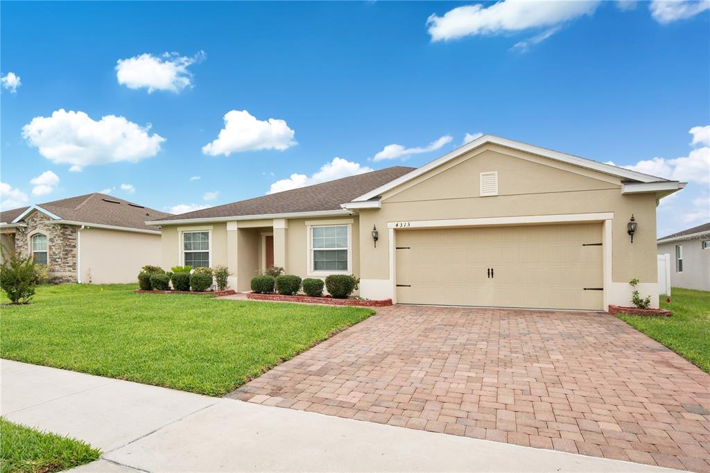 A single-story house with a tan stucco exterior, a two-car garage, and a paver driveway — 4313 TIGRIS DRIVE, APOPKA, FL