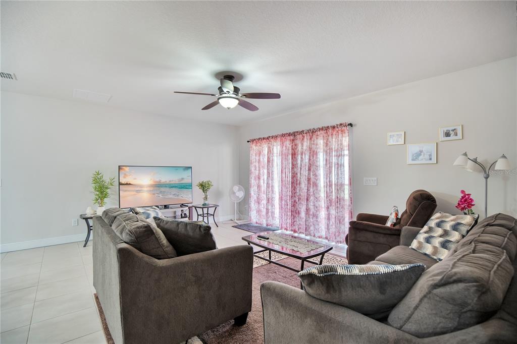A living room features a ceiling fan, a television, and a sliding glass door — 4313 TIGRIS DRIVE, APOPKA, FL
